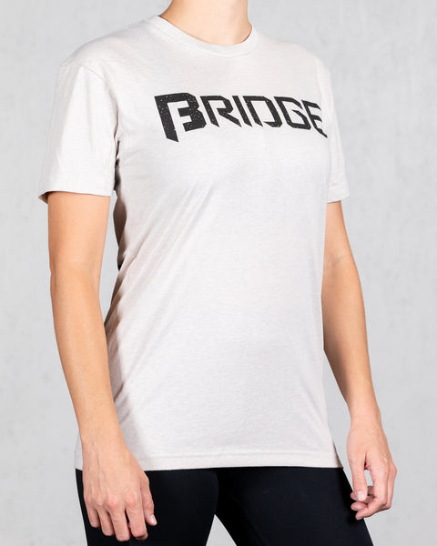 woman wearing sand colored squad tee with bridge on the front